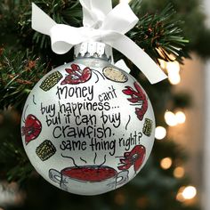 a christmas ornament hanging from a tree with writing on it that says money can't buy happiness but it can buy crawish some thing right