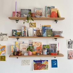 three wooden shelves filled with books on top of each other next to a white wall