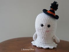 a white crocheted toy with a black hat on top of it's head