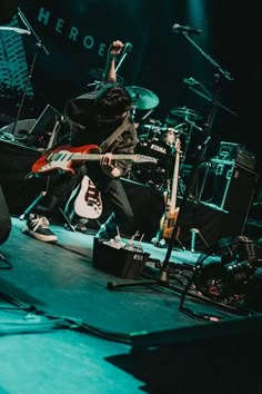 a man playing guitar on stage with other instruments