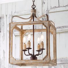 a chandelier hanging from the ceiling with three candles in front of an old door