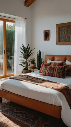 a bedroom with a large bed sitting next to a sliding glass door and potted plant