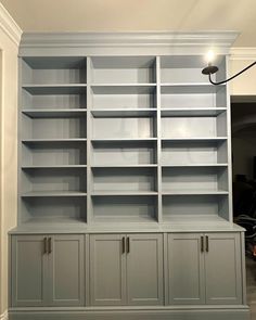 an empty bookcase in the corner of a room with two doors on each side