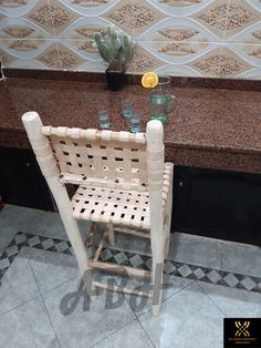 a wooden chair sitting on top of a tiled floor next to a counter with glasses