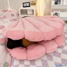 a person laying on top of a bed with a pink pillow in the shape of a mushroom