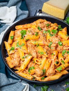 a skillet filled with pasta and meat sauce on top of a blue table cloth