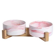 two pink marble bowls sitting on wooden stands