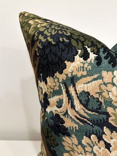 a close up of a decorative pillow on a white surface with a black and green floral pattern