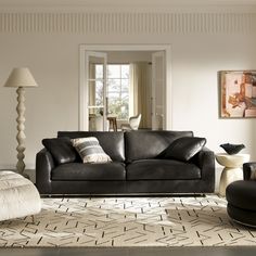 a living room with black leather furniture and white rugs on top of the floor