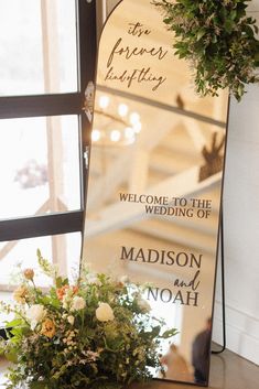 a large mirror sitting on top of a table next to a vase filled with flowers