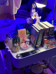 a table with books and other items on it in front of a purple lit room