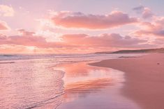 the sun is setting at the beach with waves coming in to shore and pink clouds