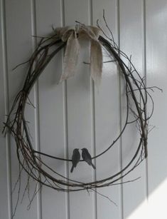 two birds sitting on a twig wreath hanging on the wall next to a door