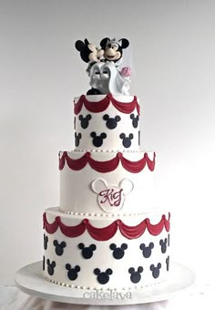 a three tiered cake with mickey and minnie mouse on top is decorated in red, white, and blue