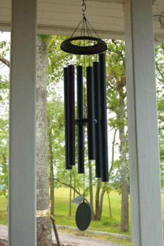 a wind chime hanging from the side of a porch with trees in the background