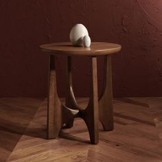 a wooden table with a white ball on top and a red wall in the background