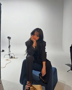 a woman is sitting on a chair in front of a photo studio with lighting equipment