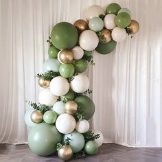 a number one made out of balloons in green and white colors with greenery on the bottom