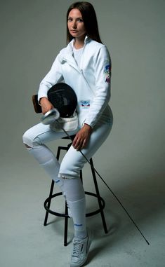 a woman sitting on top of a stool holding a helmet