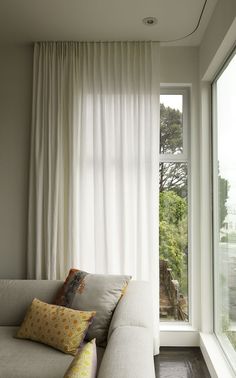 an open window with white curtains in front of it