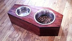 a wooden box with two metal bowls on the top and one is filled with dog food