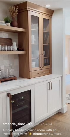 a kitchen with white cabinets and wooden shelves filled with dishes, wine glasses and other items