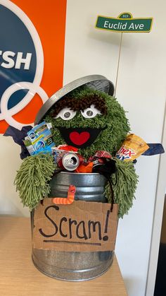 the sesame street character is sitting in a bucket filled with candy and candies while holding a sign that says scrub