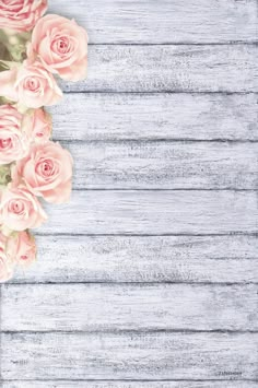 a vase filled with pink roses sitting on top of a wooden table next to a phone