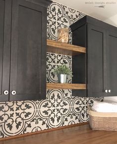 a kitchen with black cabinets and white tile backsplash, wood flooring and open shelving