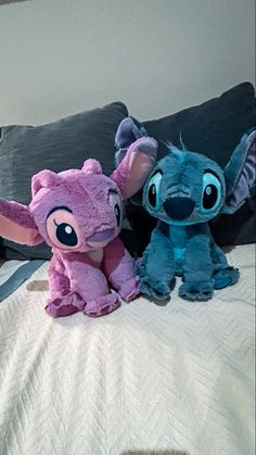 two stuffed animals sitting on top of a bed