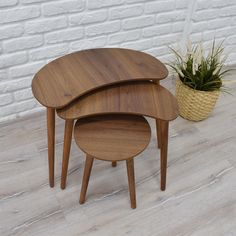 three wooden tables sitting next to each other in front of a brick wall and potted plant