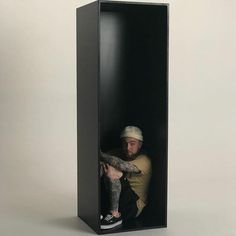 a man with tattoos sitting in a black box