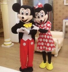 two mickey and minnie mouse mascot standing next to each other in front of a living room