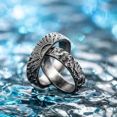 two wedding rings sitting on top of each other in front of blue water with bubbles