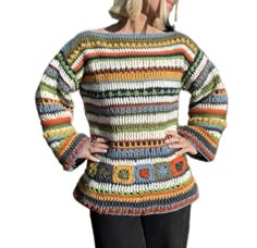 a woman wearing a multicolored sweater and black pants with her hands on her hips