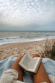 an open book is sitting on someones lap at the beach