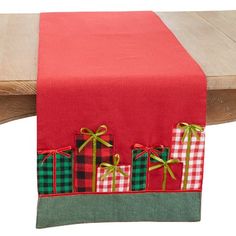 a red table runner with green and red plaid gift boxes on it, tied together