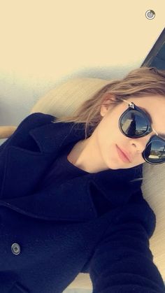 a woman wearing sunglasses laying on a couch