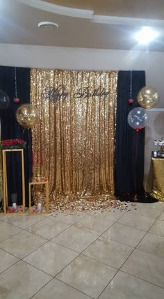 a party room with gold sequins and black drapes on the door, balloons in the air