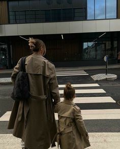 a woman and child are walking across the street