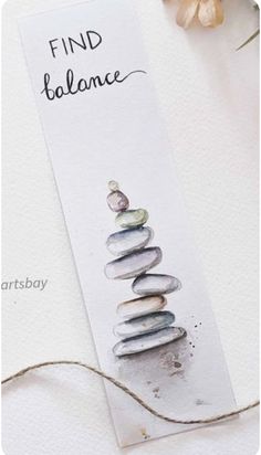 a white bookmark with some rocks on it and a flower in the background that says find balance