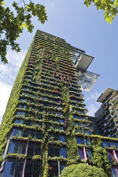 a tall building with plants growing on it's side and trees in the foreground