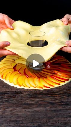 two hands holding a yellow and red plate with apples on it, while another person holds the lid