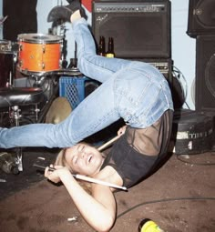 a woman laying on the ground with her legs up in the air while playing drums