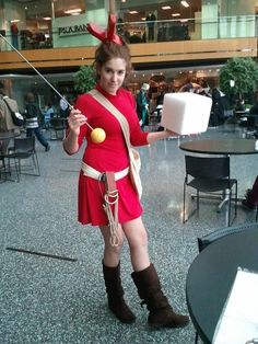 a woman dressed in costume holding a tennis racket and ball while standing next to a table