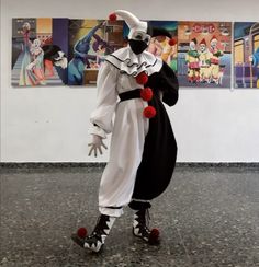 a man dressed as a clown standing in front of some pictures on the wall behind him