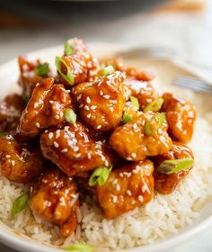 a white plate topped with rice covered in sesame seeds and chicken pieces on top of it