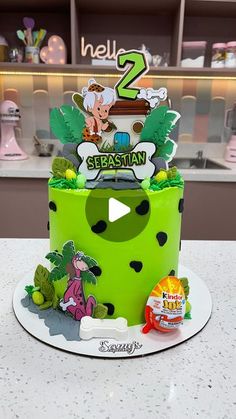 a two tiered green cake sitting on top of a white counter next to a candy bar