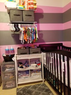 a baby's room with pink and gray stripes on the wall, crib in the foreground