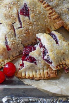 three cherry hand pies on a silver platter with cherries around the edges